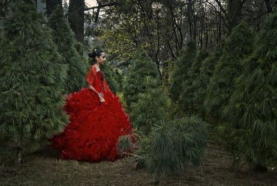 Woman standing amidst trees in forest