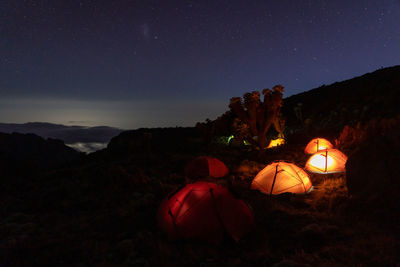 Rear view of man standing on mountain against sky at night