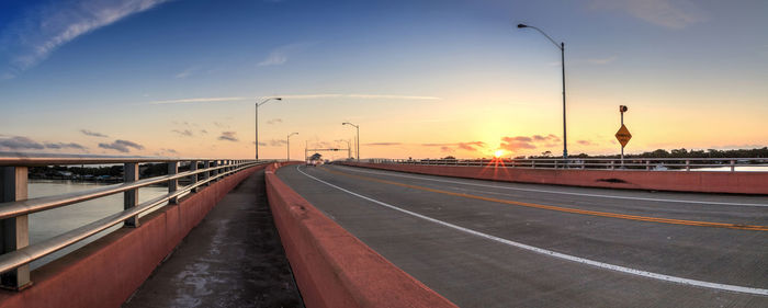 Road by street against sky during sunset