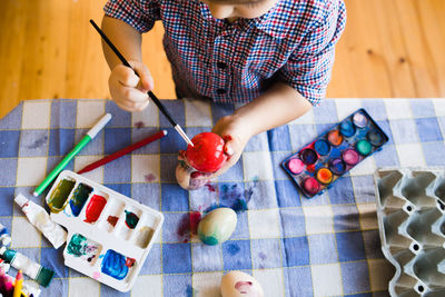 High angle view of boy painting eggs on table