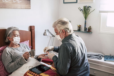 Man giving medicine to woman on bed at home