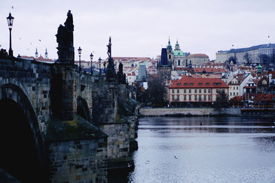 Arch bridge over river against buildings in city