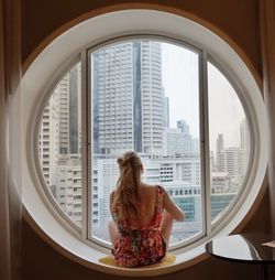 Young woman sitting on window at home