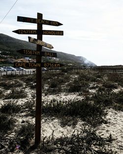 Road sign on landscape against sky