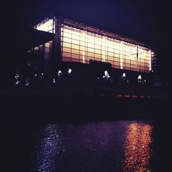 Silhouette people in illuminated building against sky at night