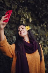 Portrait of smiling young woman standing against plants