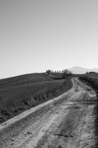 Dirt road on field against clear sky