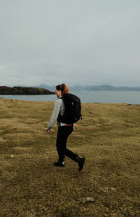 Rear view of woman standing on field against sky