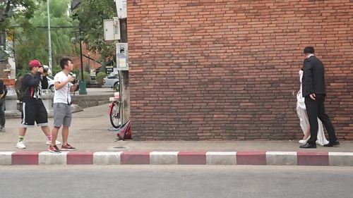 People standing by brick wall