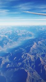 Aerial view of snowcapped mountains against blue sky