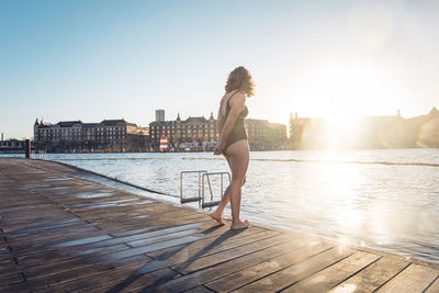 Fit woman standing alone on dock before swim in copenhagen, denmark