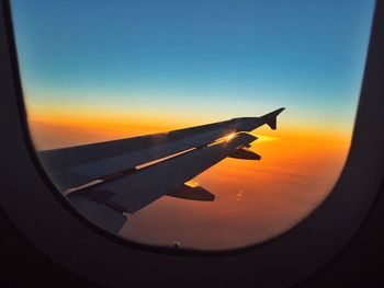 Airplane wing against sky during sunset