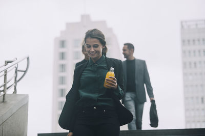 Young man holding woman standing against buildings in city