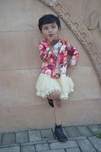 Portrait of cute girl standing against brick wall