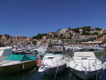 Boats moored at harbor against clear blue sky