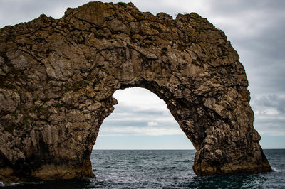 Rock formation on sea shore against sky