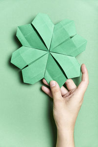 Cropped image of hand holding paper against green background