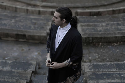 Young man looking away while standing on steps 