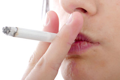 Close-up midsection of woman smoking against white background