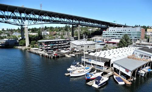 Boats moored at harbor against sky in city