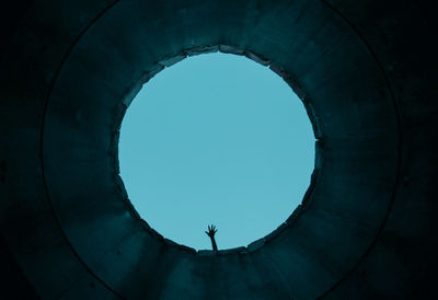 Man standing against clear blue sky seen through arch