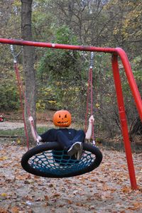 Boy sitting on swing at playground