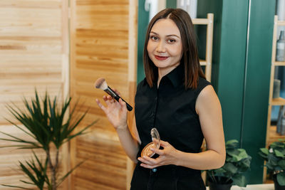 Portrait of a makeup artist girl with a brush and powder in her hands in a beauty salon