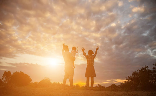 People standing on field against sky during sunset