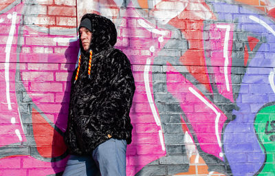 Fashionable mature man standing against graffiti wall