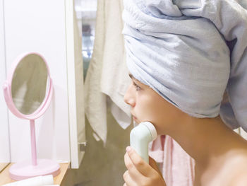 Side view of girl cleaning face at home