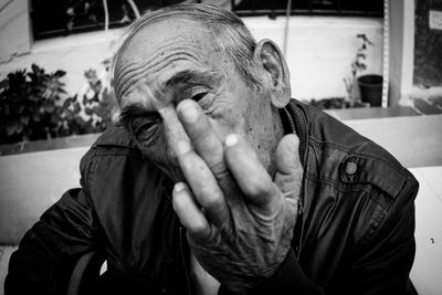 Portrait of senior man showing middle finger while sitting in city