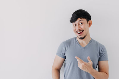 Portrait of smiling young man standing against white background