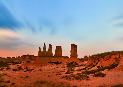 Rock formations on landscape against sky during sunset