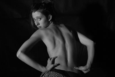 Portrait of shirtless woman against black background