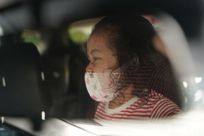 Rear view of woman looking at while sitting in car