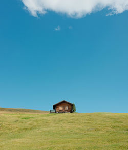 House on field against clear blue sky