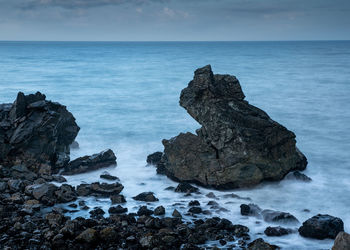 Rocks on sea shore against sky