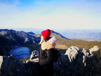 Side view of woman standing on mountain against sky