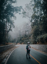 Rear view of man walking on road in forest