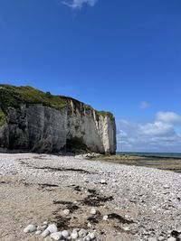 Rock formations on beach against blue sky