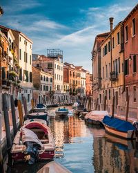 Boats moored in canal amidst buildings in city