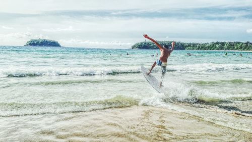 Man jumping on beach against sky