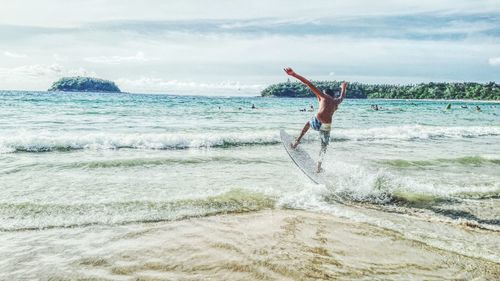 Man surfboarding on shore at beach against sky