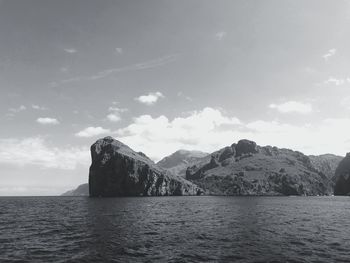 Scenic view of sea by mountains against sky