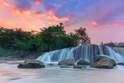 Scenic view of waterfall against sky at sunset