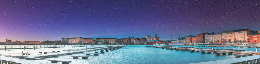 Buildings by river against sky at night