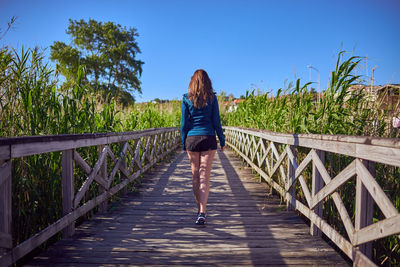 Rear view of woman walking on footbridge