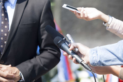 Cropped hand interviewing businessman with microphone