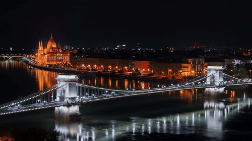 Illuminated bridge over river at night