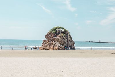 People on rock by sea against sky